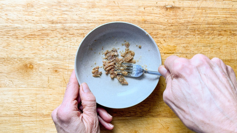 Mashing sardines in a bowl with a fork
