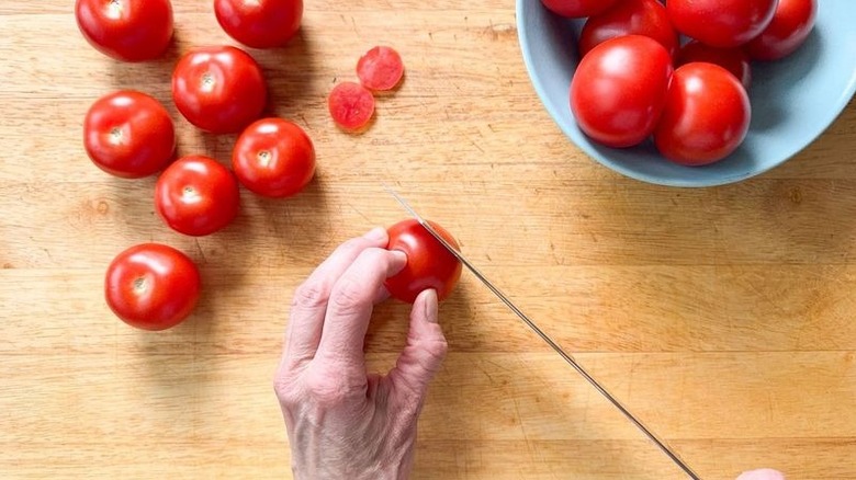 Cutting thin slice from bottoms of campari tomatoes