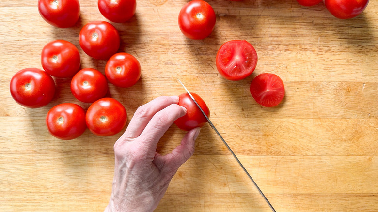 Cutting tops off of campari tomatoes on cutting board