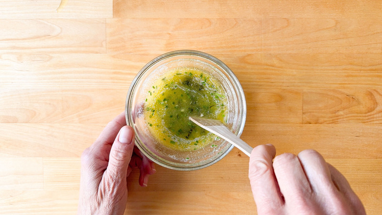 Stirring herbed garlic butter in glass bowl