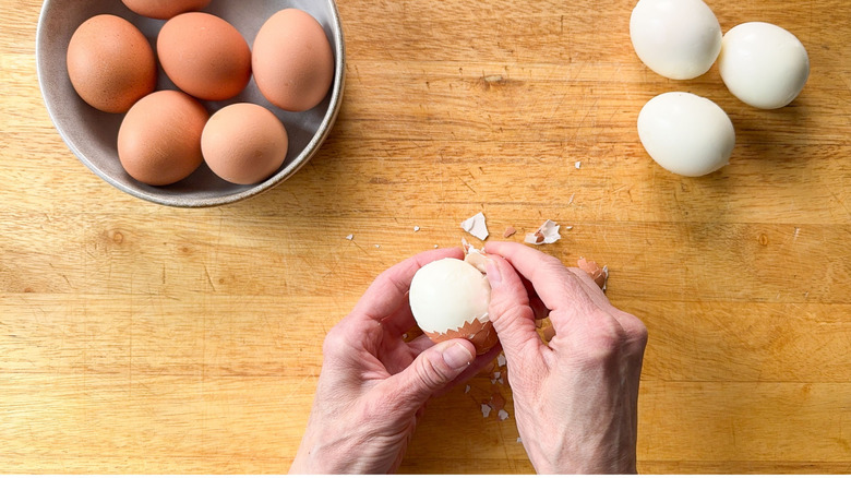 Peeling hardboiled eggs on cutting board