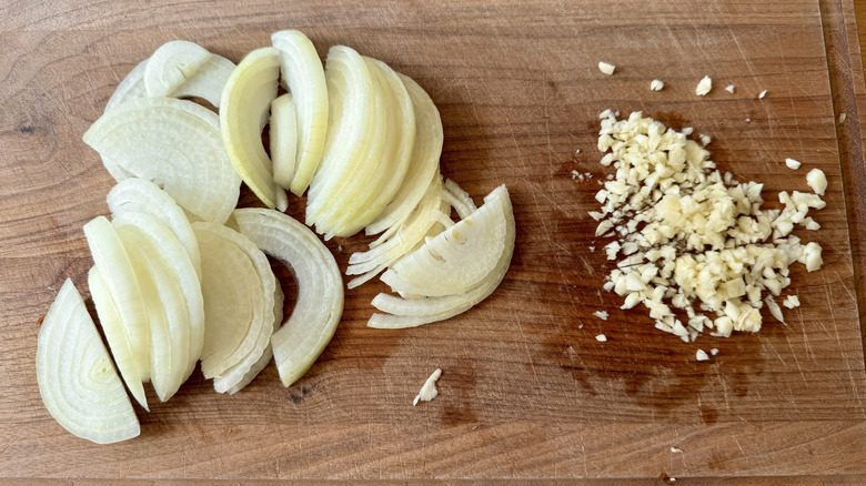 Sliced onions and minced garlic on cutting board