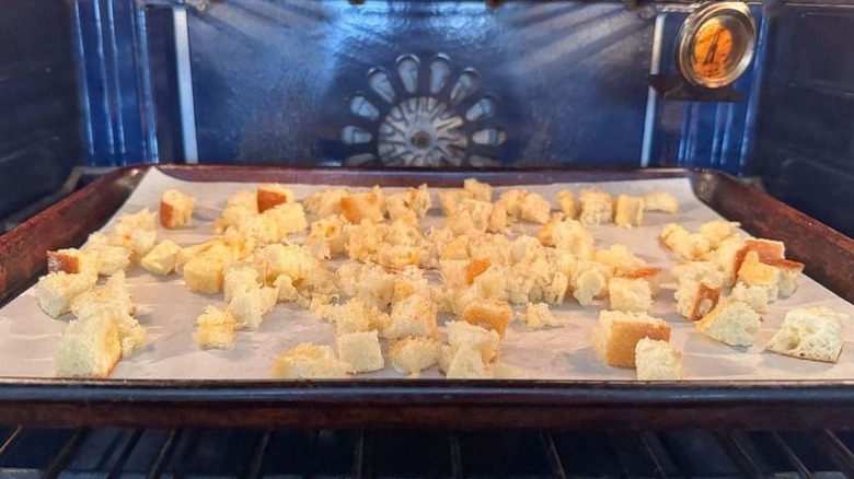 Croutons baking on parchment-lined baking sheet in oven