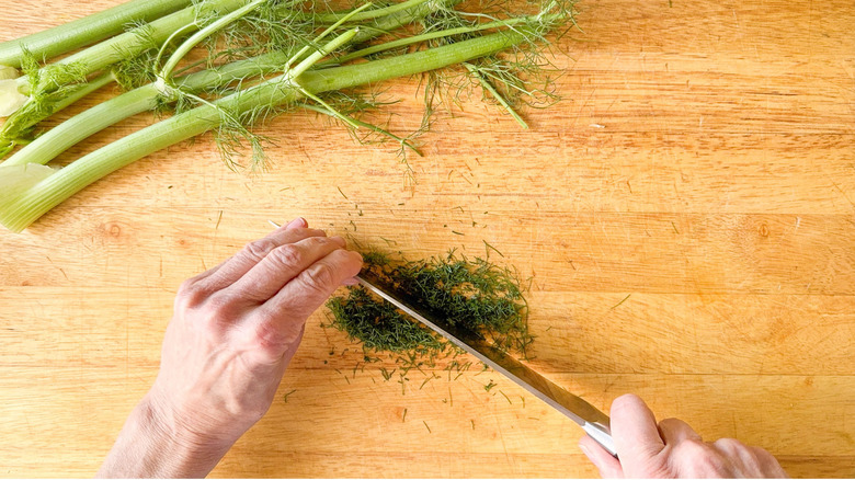 Chopping fresh fennel fronds on cutting board