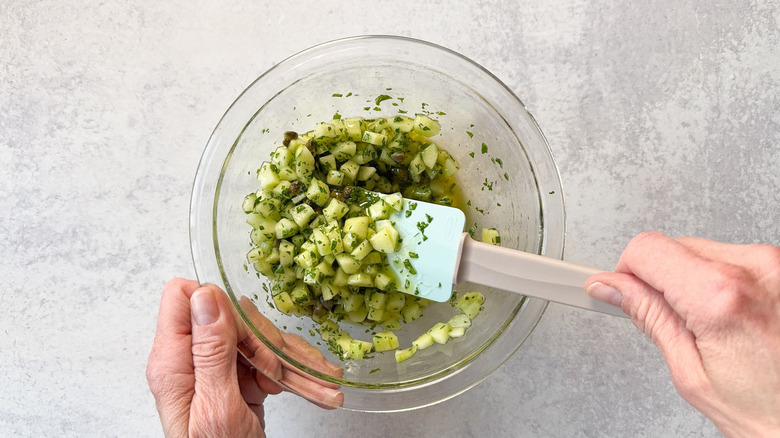 Mixing cucumber dressing in glass bowl with spatula
