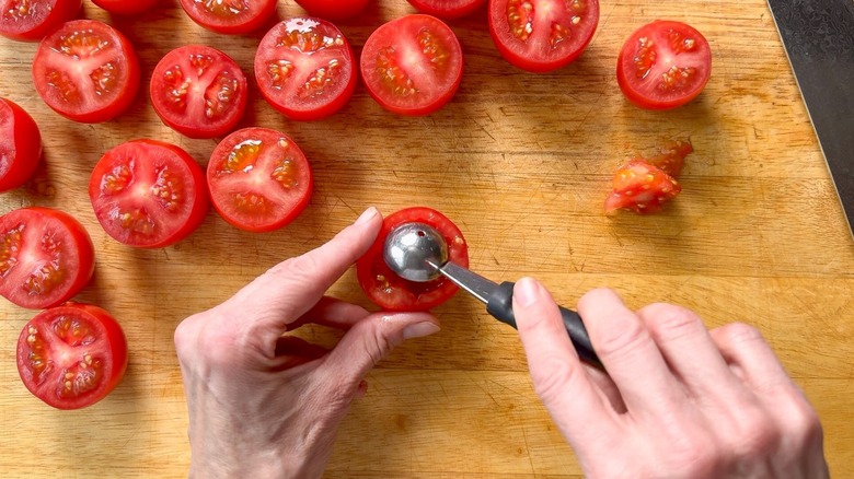 Scooping tomato seeds out of cut campari tomatoes with melon baller
