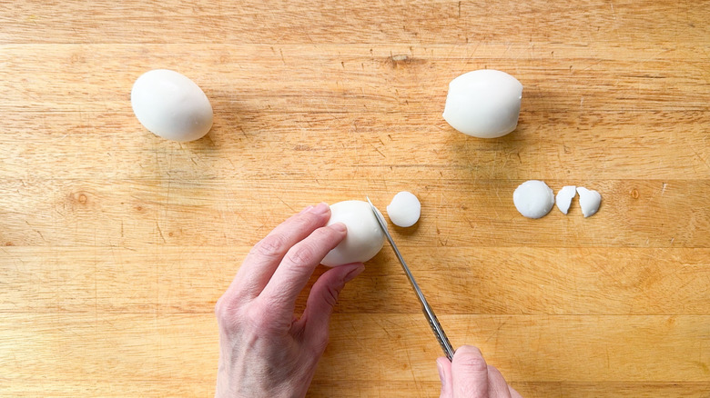 Trimming the ends off hard boiled eggs on cutting board