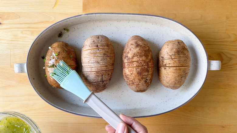 Basting herbed butter on Hasselback potatoes