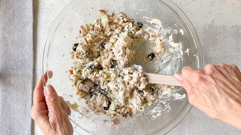 Mixing triple anise chicken salad with rubber spatula in glass bowl