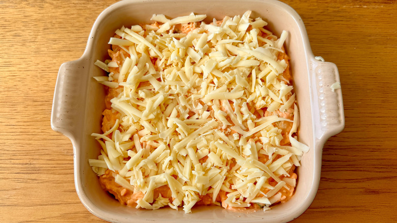 Dip in dish with shredded cheddar on top