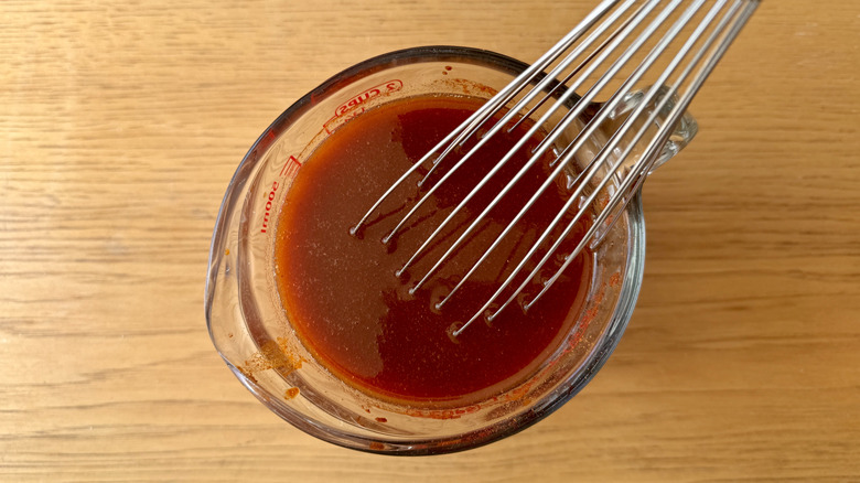 Whisking brisket cooking liquid in measuring cup