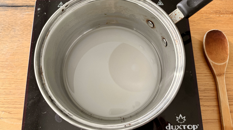 Heating sugar with water in saucepan