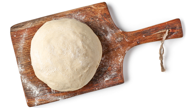 fresh raw dough on wooden board isolated on white background, top view