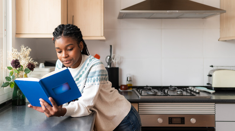 young woman reading a book in the kitchen