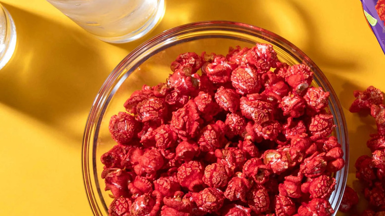 A bowl of red Takis Fuego popcorn sitting on a yellow table
