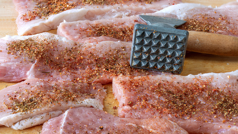 Pork chops being tenderized with a meat mallet