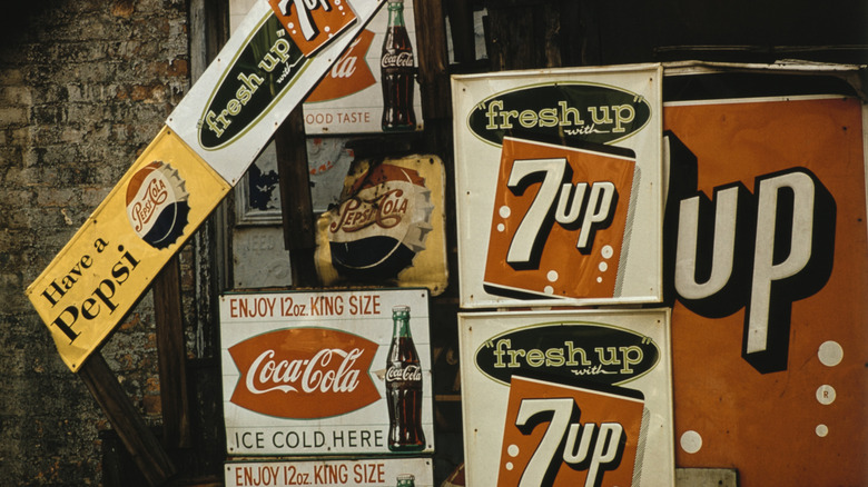 Vintage advertising signs for 7 Up, Pepsi, and Coca-Cola, the 7 Up sign featuring the slogan "fresh up with 7 Up."