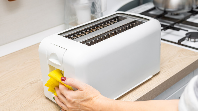 Person wiping down toaster with cloth