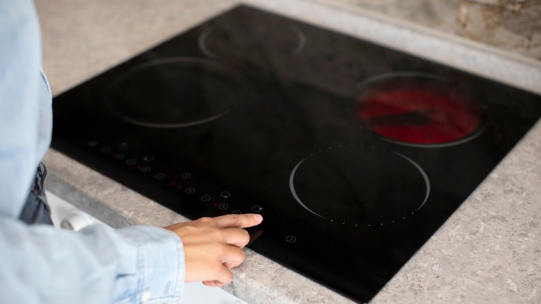 a woman using a modern glasstop induction hob
