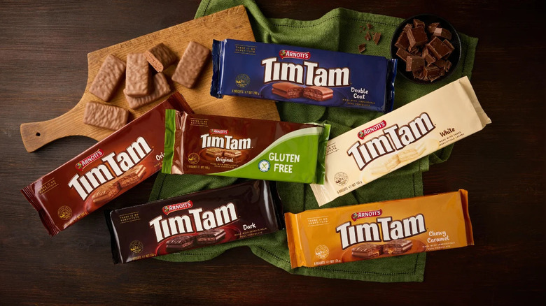 Packages of Tim Tam next to biscuits on a wooden cutting board