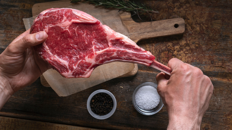 man holding tomahawk steak
