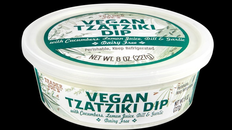 A container of Trader Joe's vegan tzatziki dip on a black background