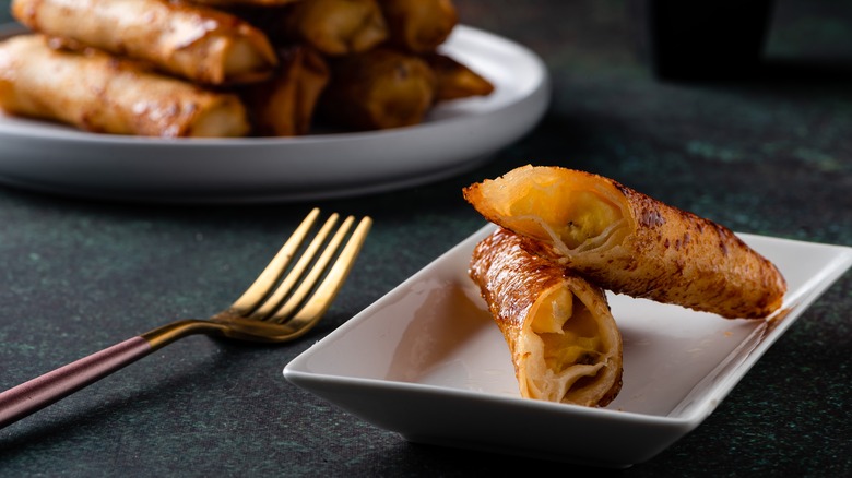 One sliced turon with fork and pile of turon on plate in background
