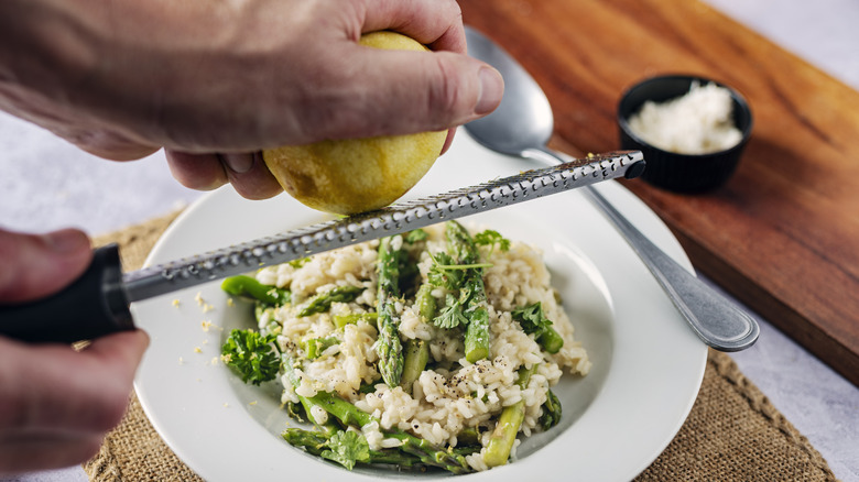A person zesting a lemon into a rice dish