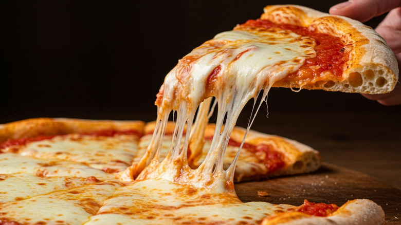A person picking up a piece of cheese pizza