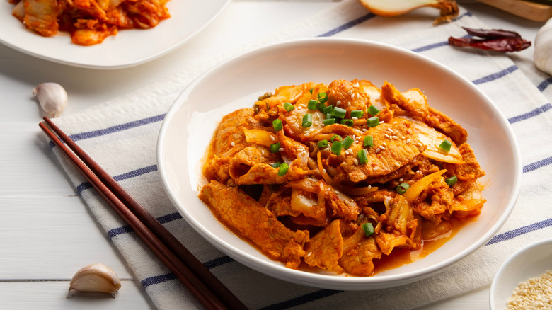 bowl of sliced pork and kimchi and chop sticks