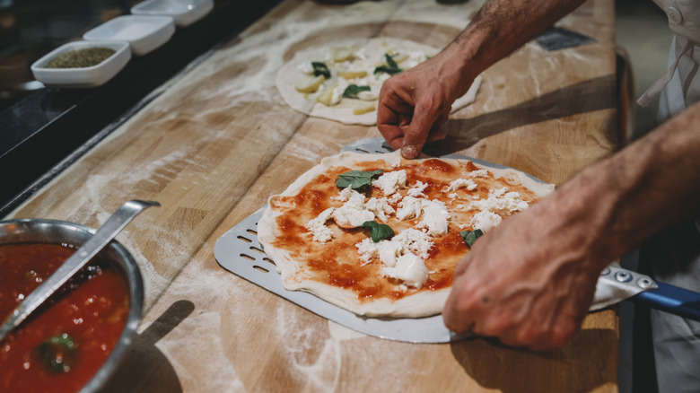 A pizza chef preparing a margherita for the oven