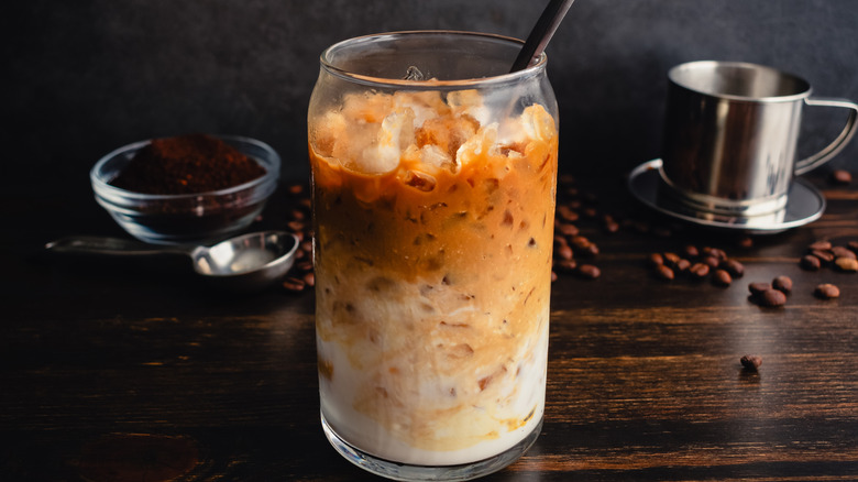 a stylish glass of Vietnamese yogurt coffee with a black straw on a dark brown table