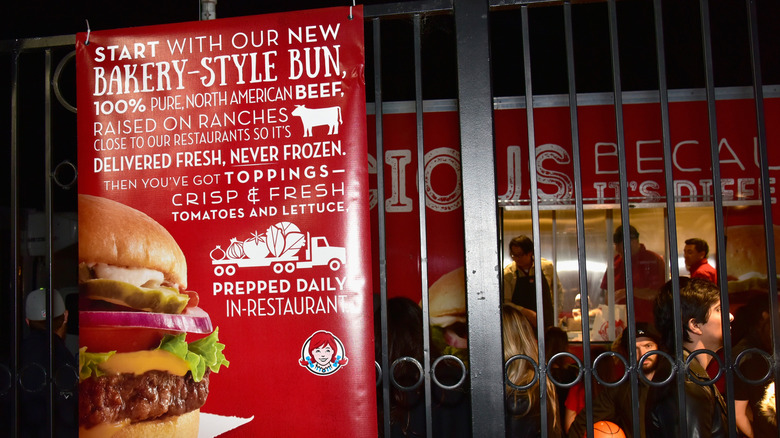 A Wendy's ad on a gate in front of a food truck