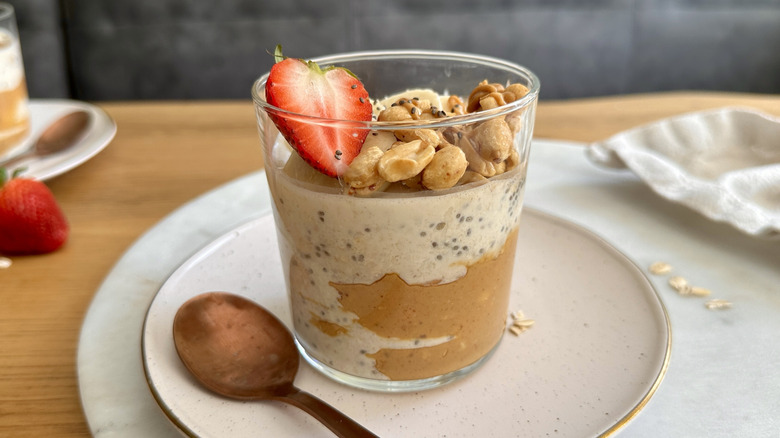 Peanut butter overnight oats in jar topped with peanuts and strawberry slice