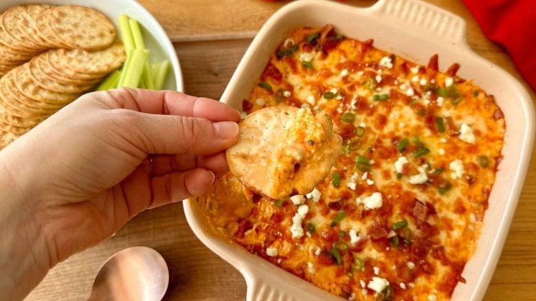 Hand holding chip with Buffalo chicken dip