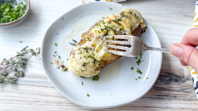 Extra cheesy Hasselback potato on plate with fork