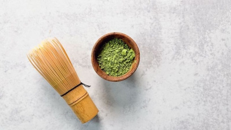 Matcha powder in wooden bowl with bamboo whisk