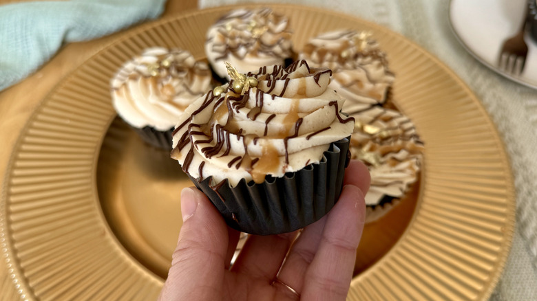 Hand holding chocolate stout cupcake with frosting