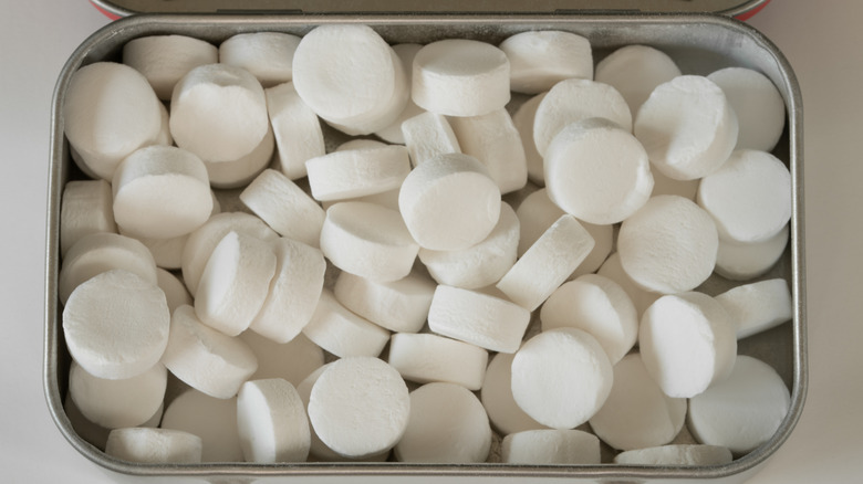 A close-up of the inside of a full tin of white breath mints.
