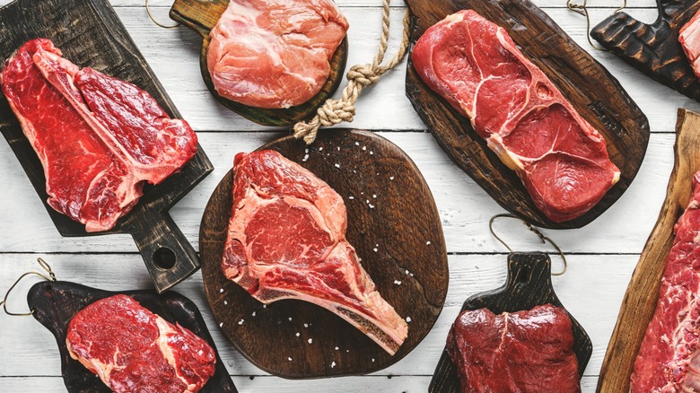 Several cuts of raw steak on cutting boards
