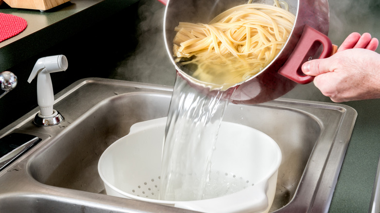 straining pasta into colander in sink